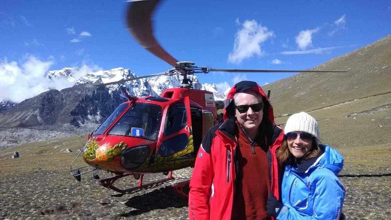 Couple in front of a helicopter on an Everest Base Camp helicopter tour.