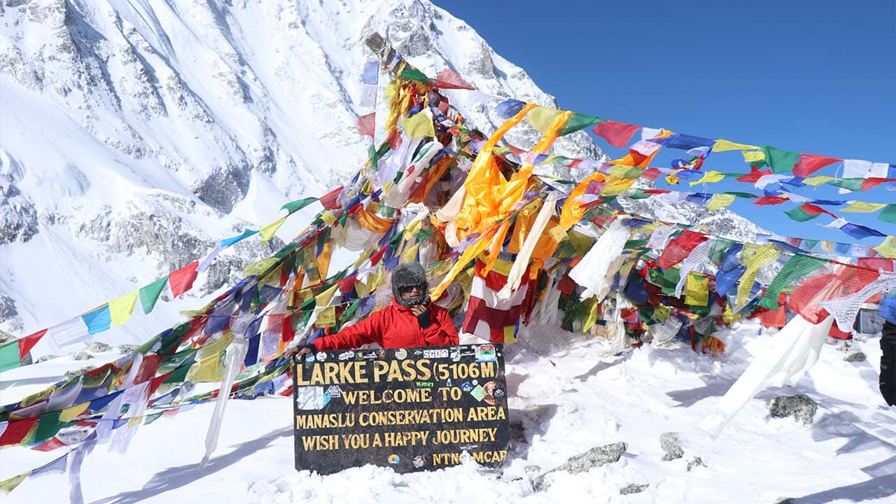 Trekker at the snowy Larkya La Pass (5,106m) summit during the 14 days Manaslu Circuit Trek.