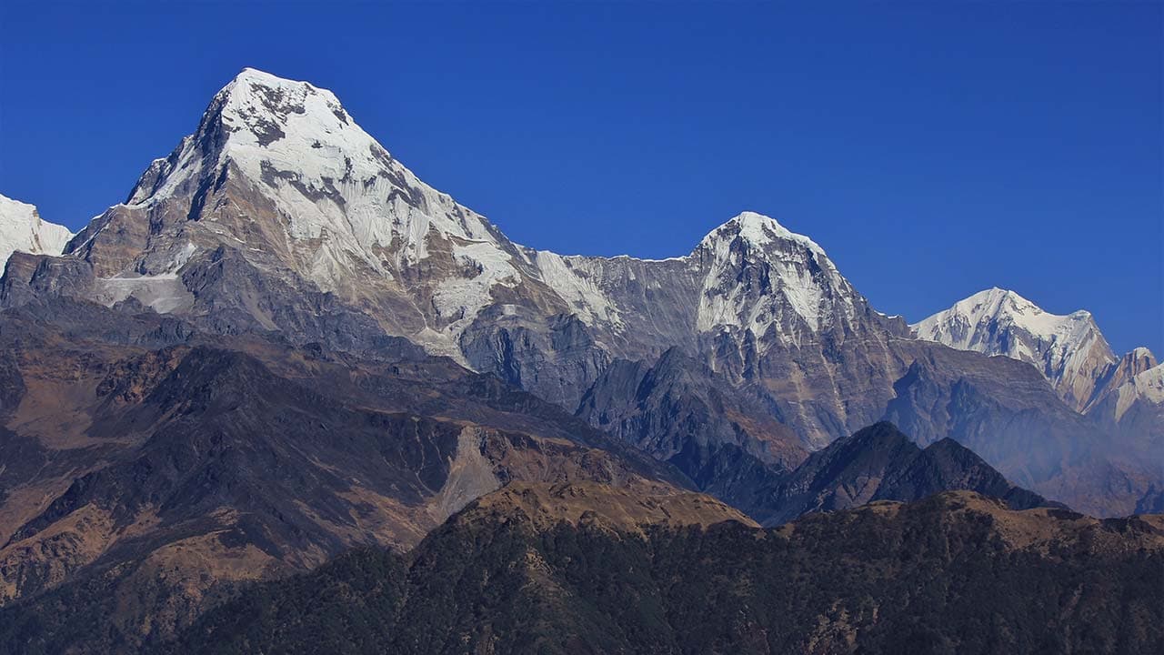 Clear, close-up view of the snow-capped Annapurna South and Hiunchuli peaks rising above rocky ridges, as seen from the Mohare Danda Trek.