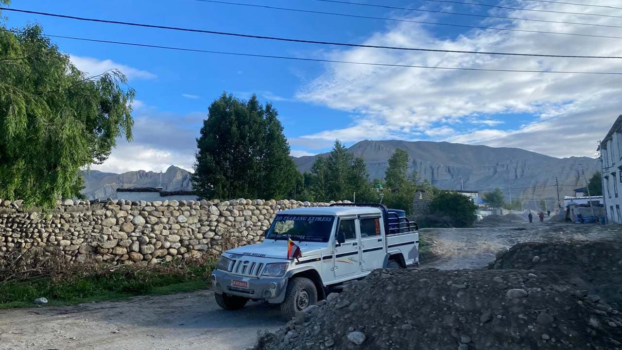 White off-road jeep parked by a traditional stone wall on the Upper Mustang Jeep Tour.