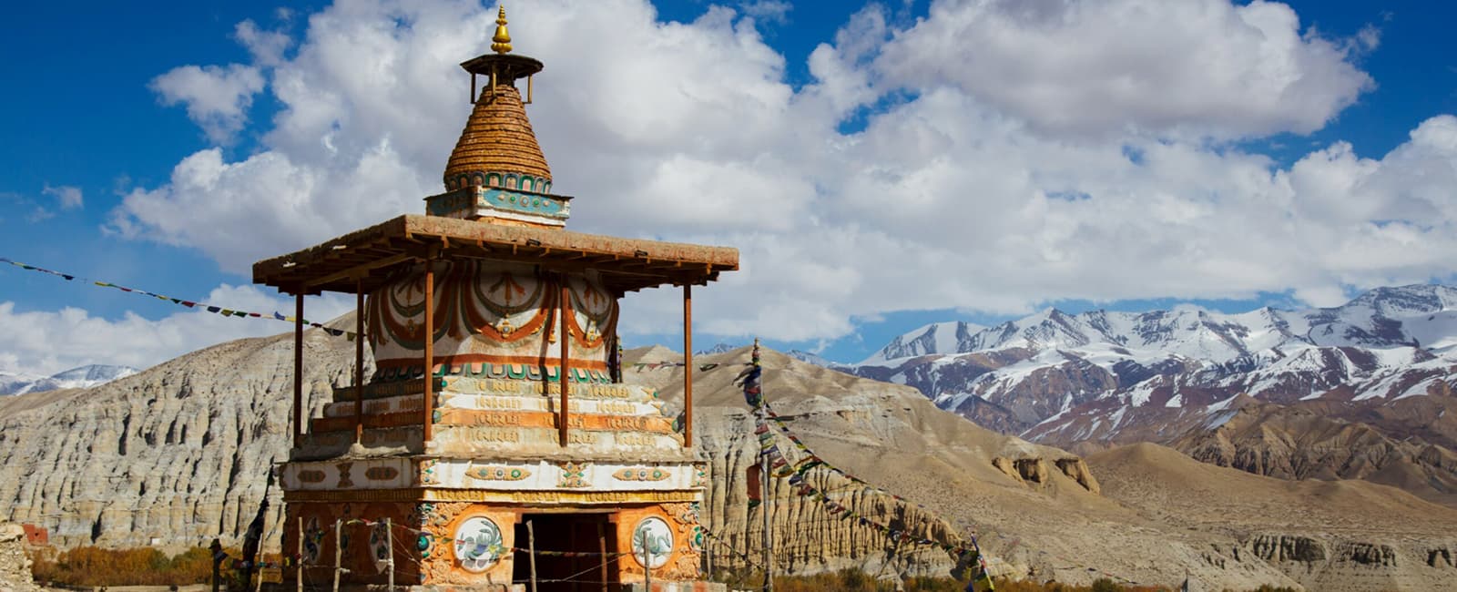 Panoramic-snow-capped-mountain-trekking-trail-in-Nepal-under-a-clear-blue-sky.